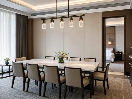 Linear multi-pendant chandelier over a rectangular dining table in a hotel setting