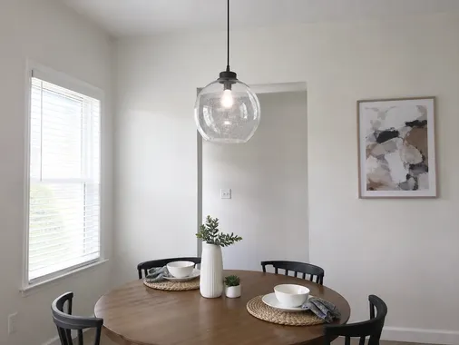 Single glass pendant fixture over a round dining table