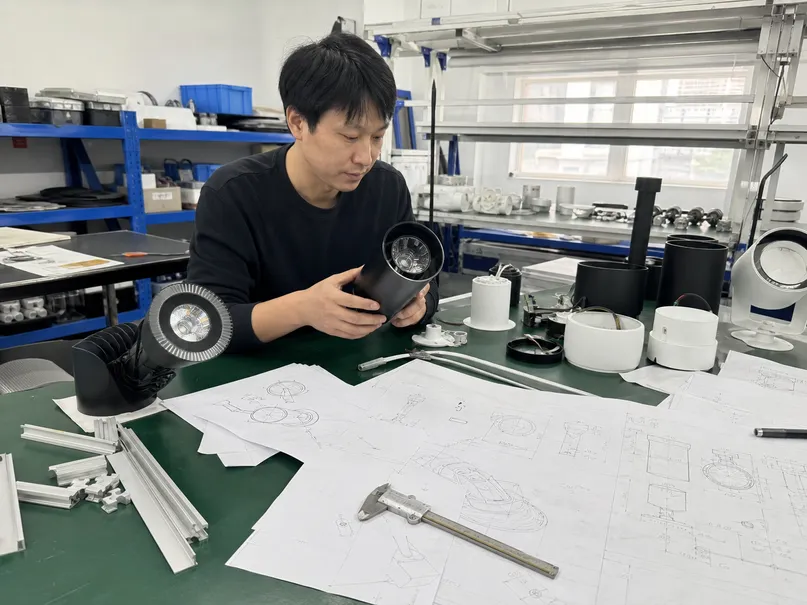 Custom lighting development process showing prototype fixtures and engineering drawings