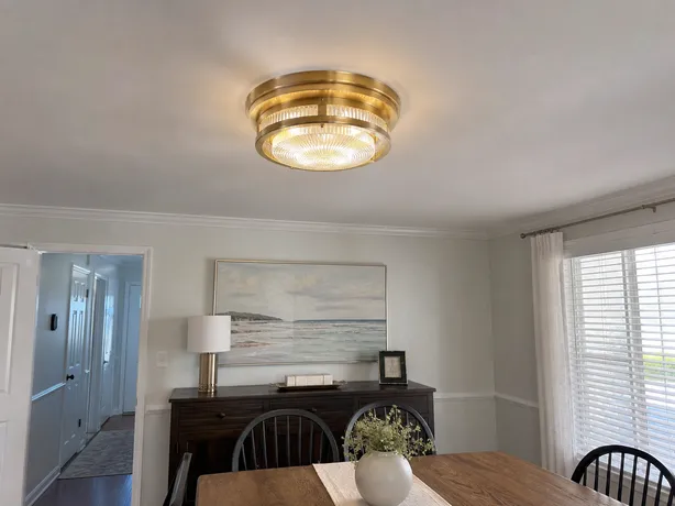 Decorative flush mount ceiling light in a dining room setting with brushed gold finish