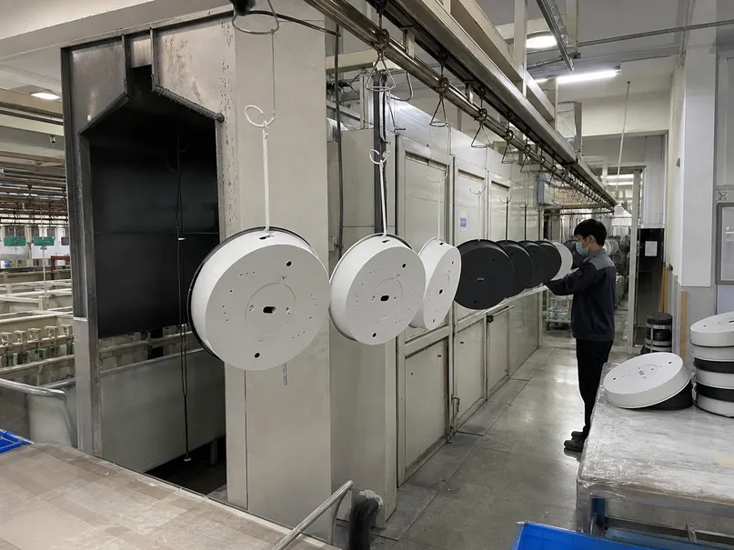 Powder coating line applying consistent matte finish to modern ceiling fixture housings