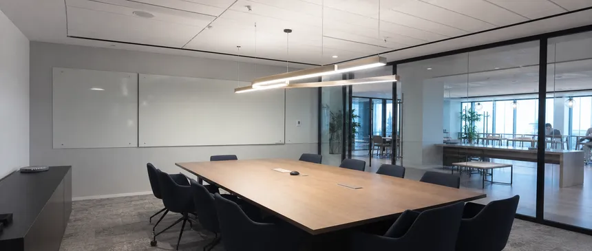 Linear chandelier lighting over conference table in commercial office space