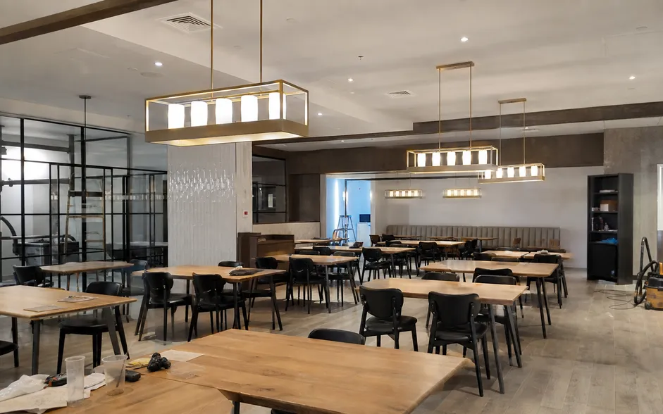 Linear chandelier lighting installed over restaurant dining tables in hospitality fit-out