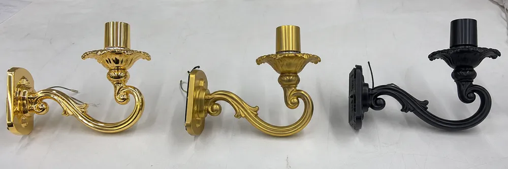 Side-by-side comparison of electroplated gold, PVD champagne gold, and matte black powder coat finishes on luxury chandelier arms