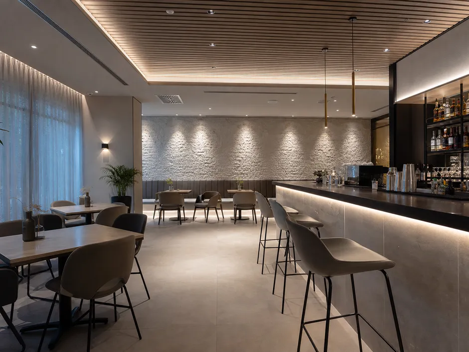 Architectural accent fixtures and linear profiles providing layered illumination in a restaurant and bar setting