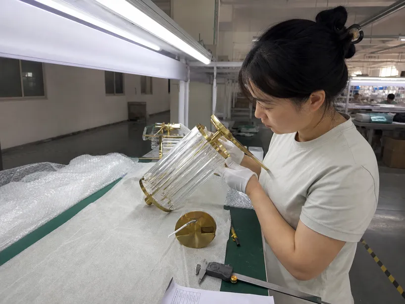 Quality control inspector examining decorative lighting fixture finish under standardized D65 lighting