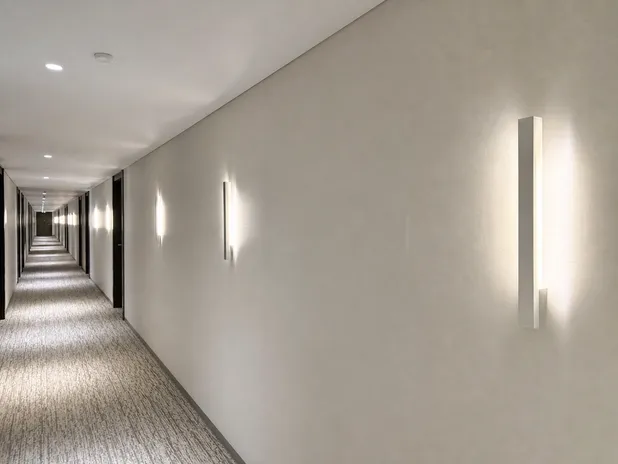 Minimalist wall sconces in linear geometric forms for hotel corridors and commercial spaces