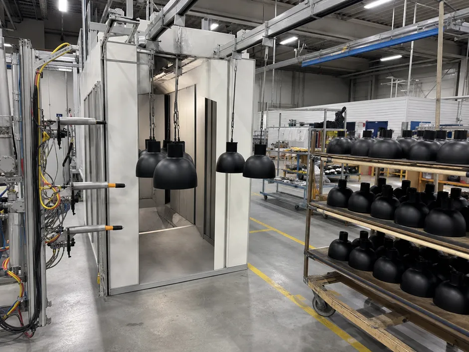 Automated powder coating application line producing consistent matte black finish on modern lighting fixtures
