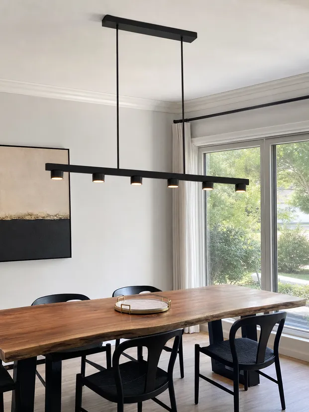 Modern linear chandelier in matte black finish with multiple light points over dining table