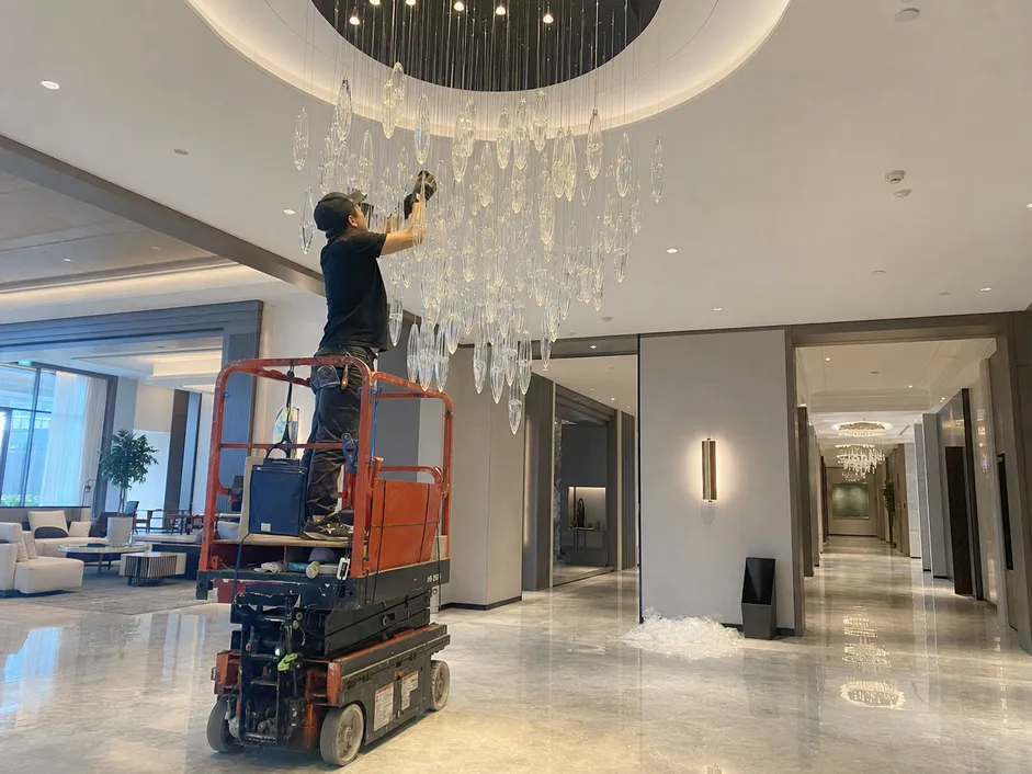 Custom chandelier installation in hotel lobby with coordinated corridor fixtures
