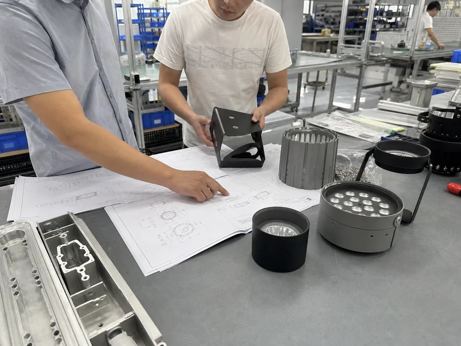 Engineering drawings being reviewed alongside production fixture samples