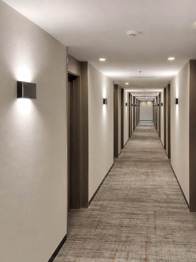 Custom wall sconces installed in hotel corridor showing consistent finish across multiple fixtures