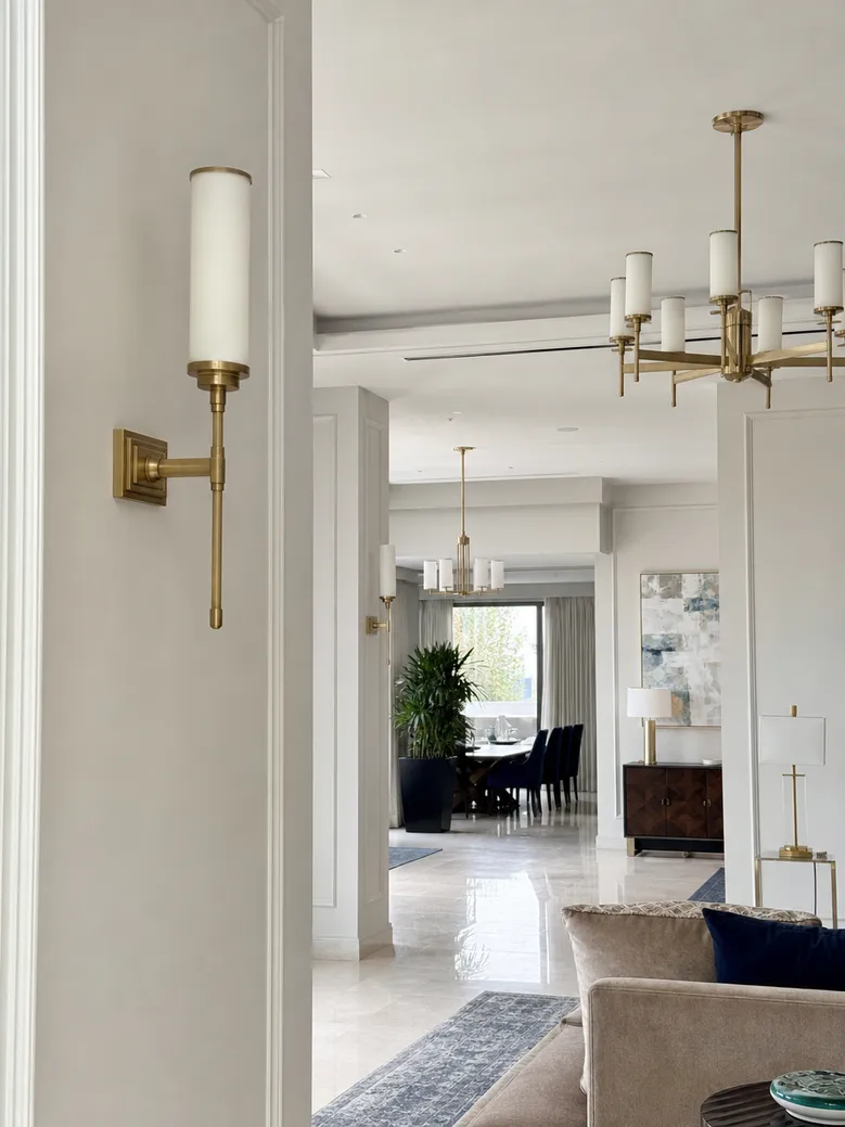 Custom wall sconces in luxury villa interior with coordinated pendant and chandelier finishes