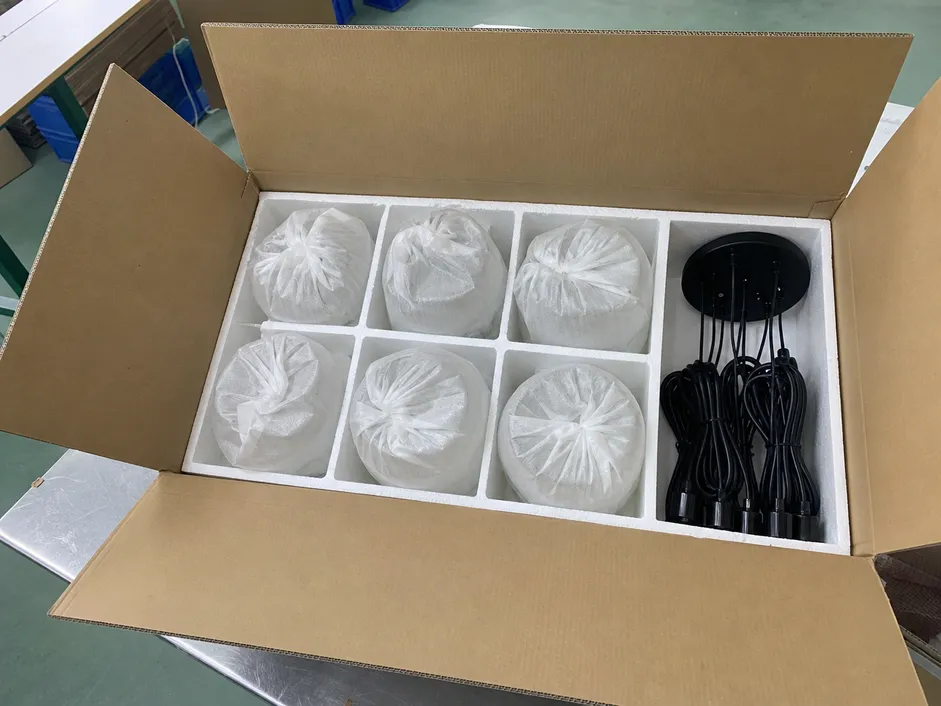 Export packaging for cluster pendant lighting showing foam-wrapped glass shades and molded inserts