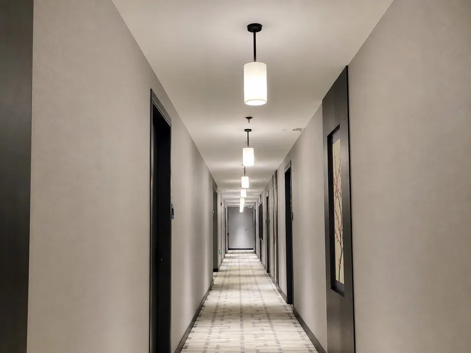 Cylinder pendant lighting installed in a hotel corridor — consistent alignment across multiple units