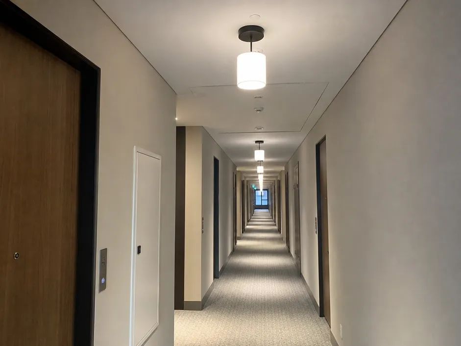Cylinder pendant lighting installed in a hotel corridor — repeating fixtures creating visual rhythm