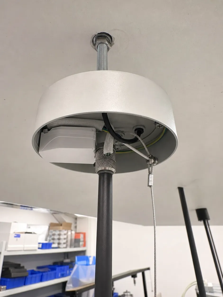 Detailed view of entryway pendant lighting suspension system showing threaded rod, canopy, cord grip mechanism, and safety cable