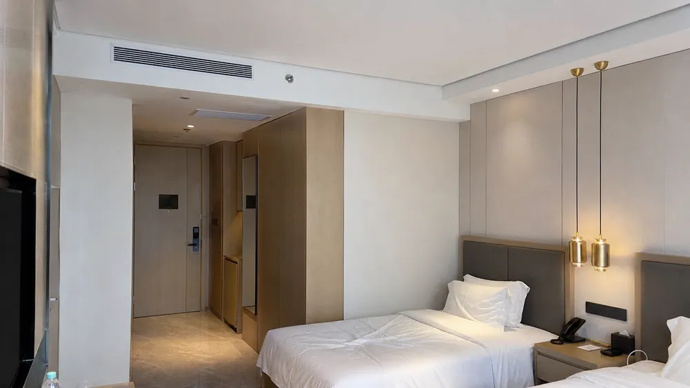 Gold pendant lighting installed in hotel corridor and guest room environment showing batch finish consistency