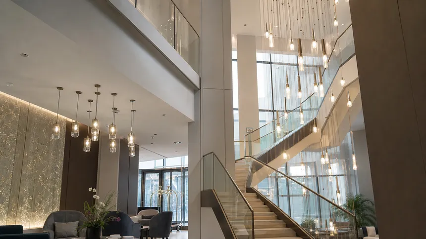 Pendant lighting installation in a hotel lobby with cluster fixtures and long-drop staircase designs