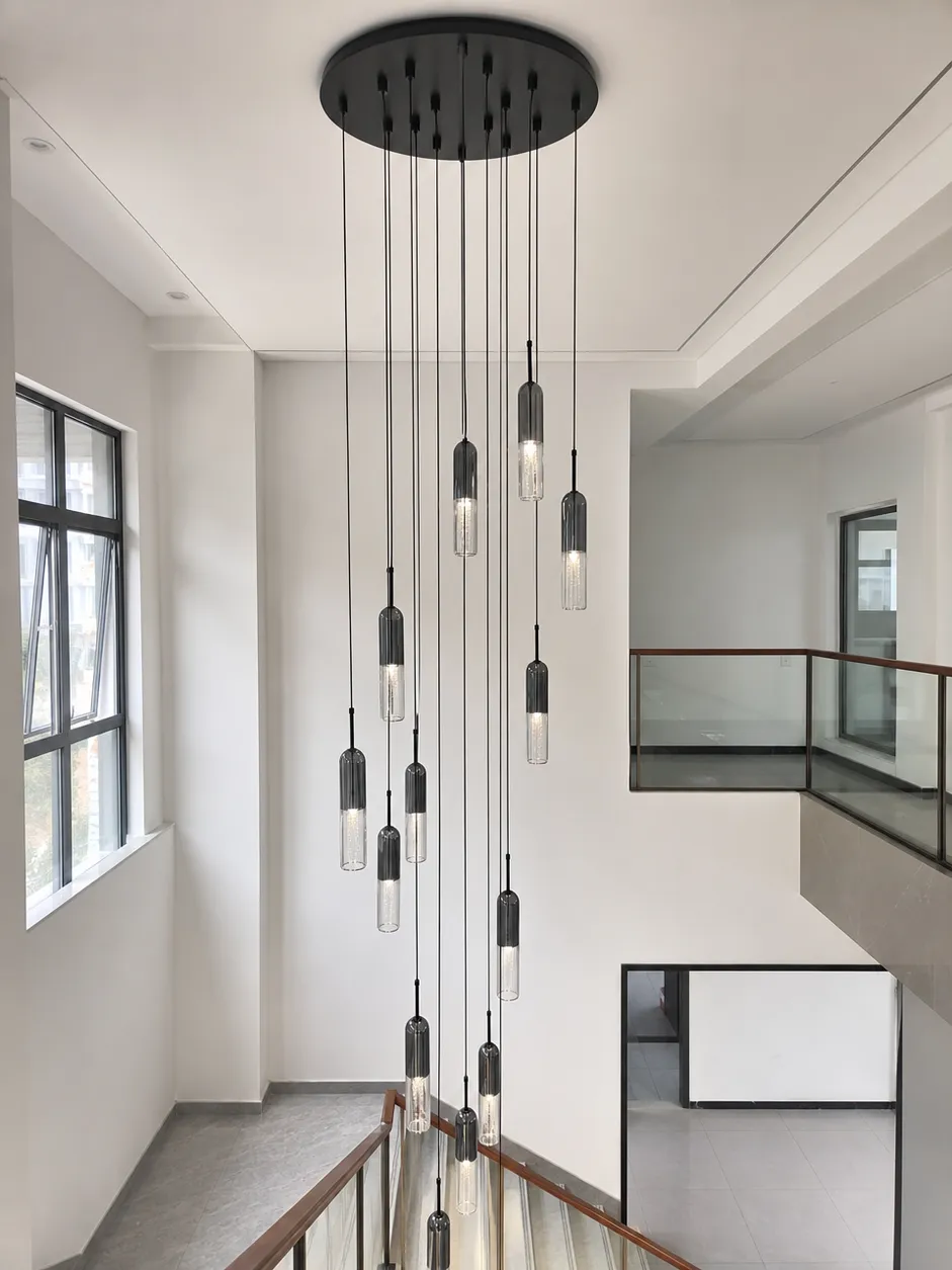 Long-drop pendant lighting in a staircase atrium showing custom suspension length configuration