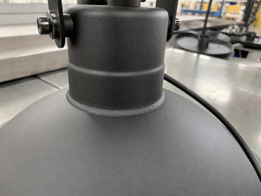 Close-up of matte black powder coat finish on industrial pendant lighting showing consistent coating thickness at weld seams