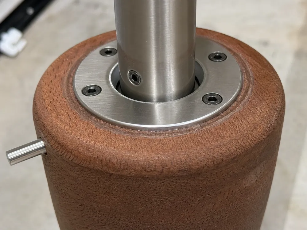 Close-up of wood-to-metal joint showing mechanical register and epoxy bond on a wood pendant fixture