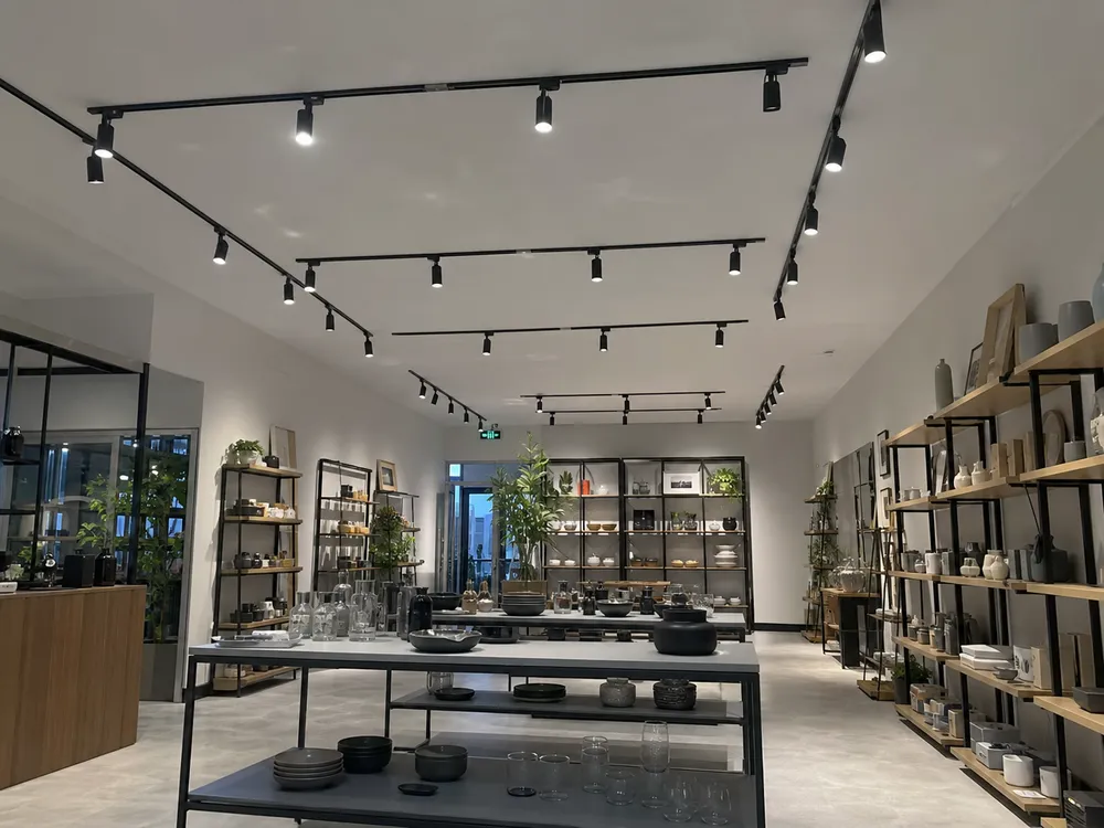 Adjustable spotlights installed in retail store fit-out with beam angles covering display tables and feature walls