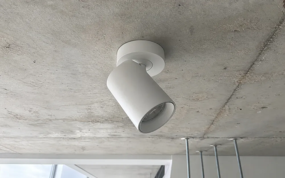 Surface-mounted ceiling spotlight on concrete slab — single gimbal installation point