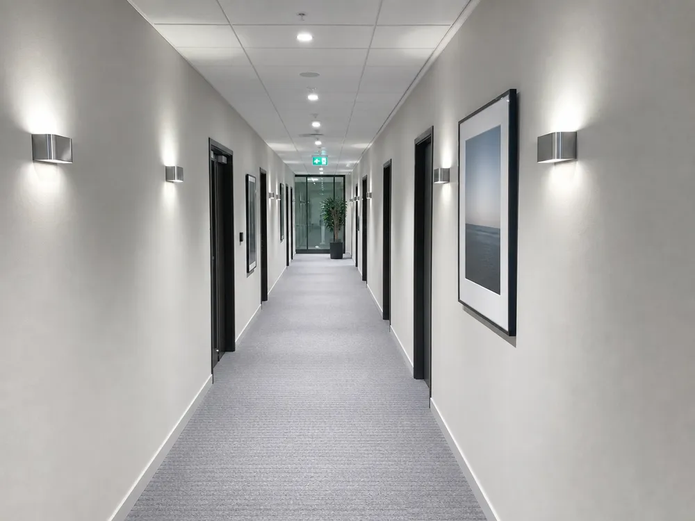 Commercial office corridor with wall sconces paired with recessed ceiling fixtures for uniform lux distribution