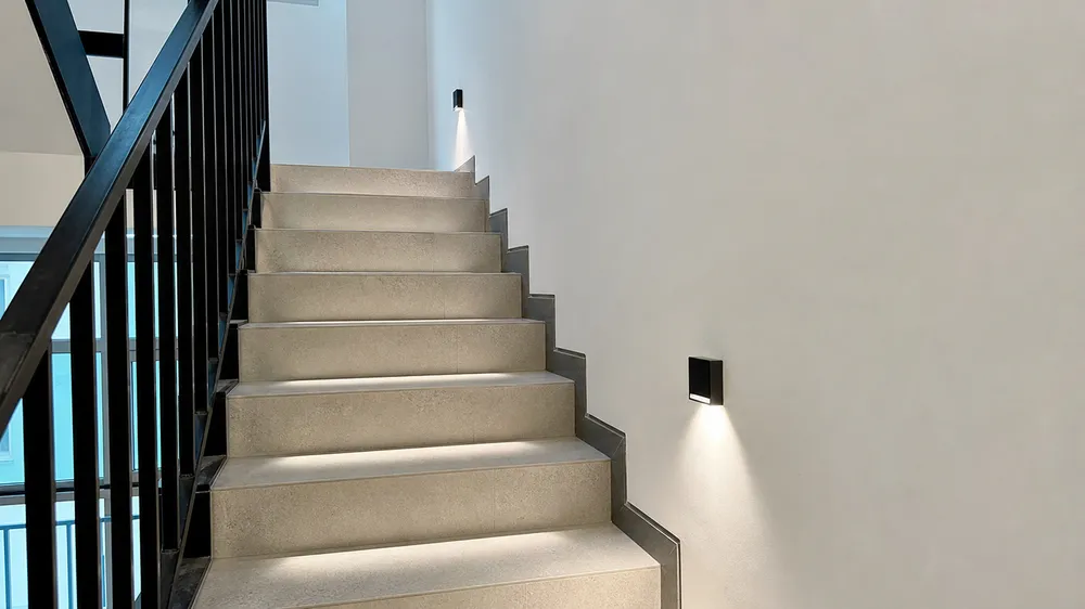 Stairway wall sconce showing compact wall projection and downward light distribution pattern on stair treads
