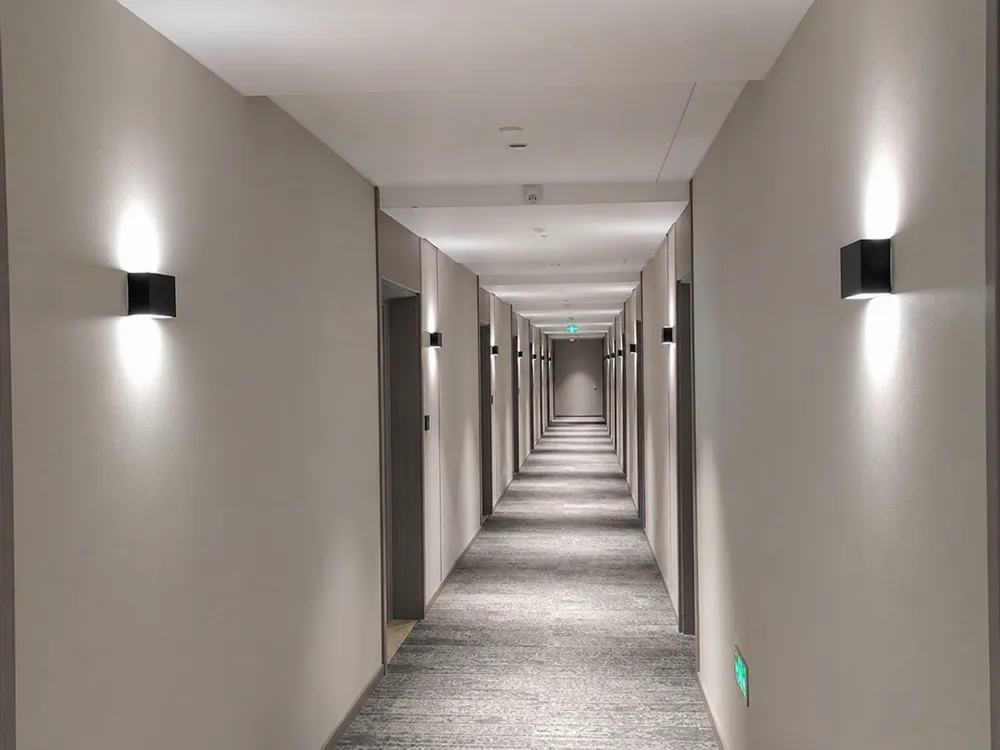 Sequential wall lighting installation along a hotel corridor demonstrating batch consistency