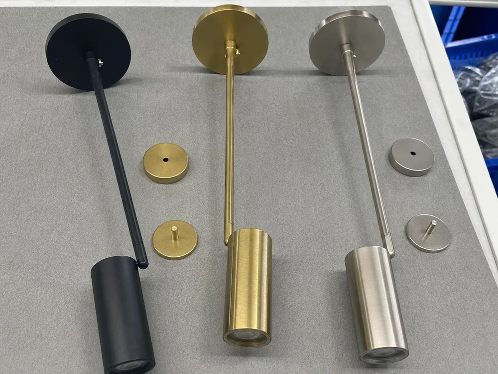 Modern wall lighting finish samples showing matte black, brushed gold, and brushed nickel options