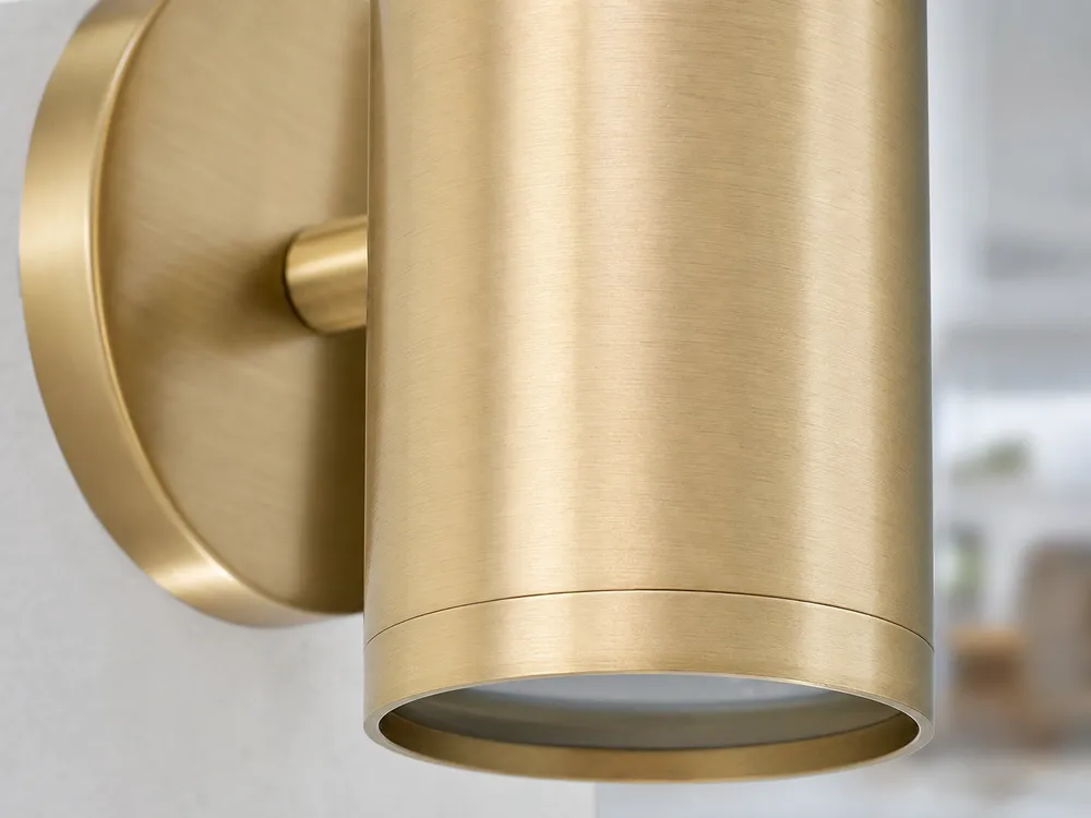 Close-up of brushed gold finish on a modern cylindrical wall sconce showing surface consistency