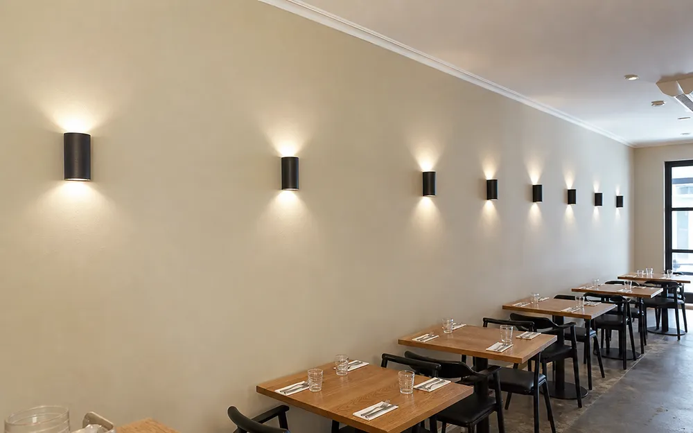 Identical modern wall sconces installed across restaurant interior for visual consistency