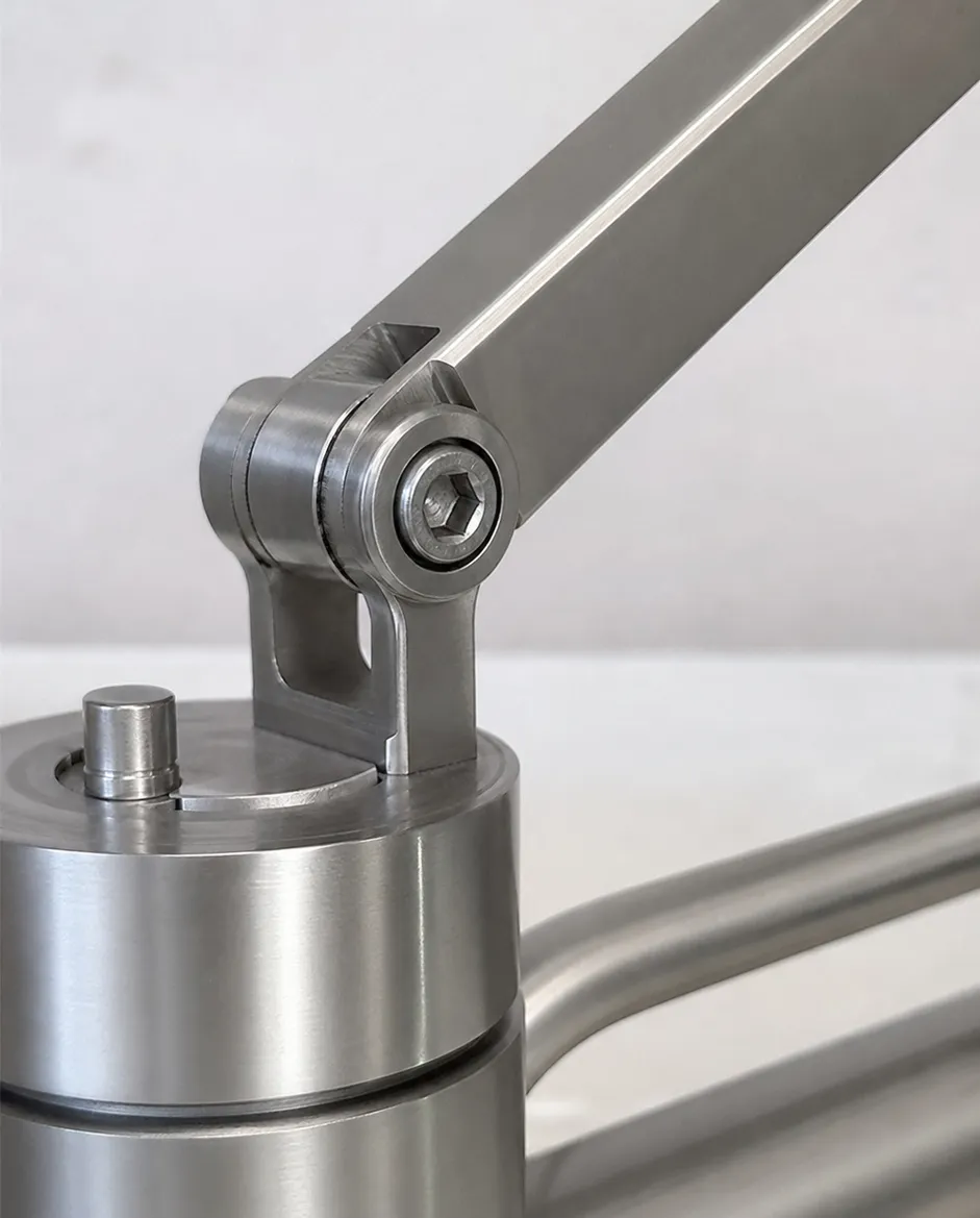 Close-up of adjustable arm pivot mechanism showing machined bearing surfaces and locking screw