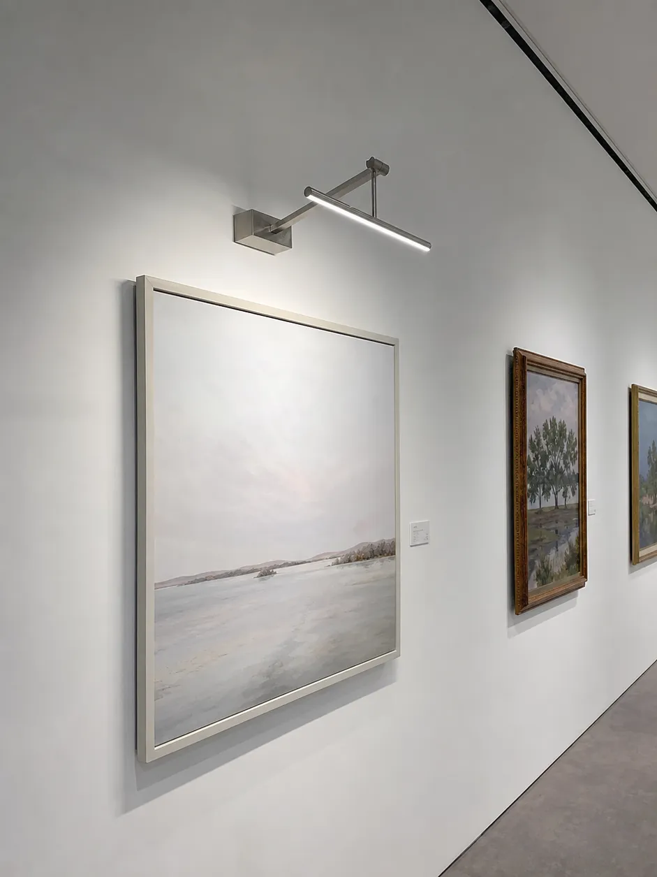 CRI 95+ adjustable arm picture light illuminating framed artwork in a gallery setting
